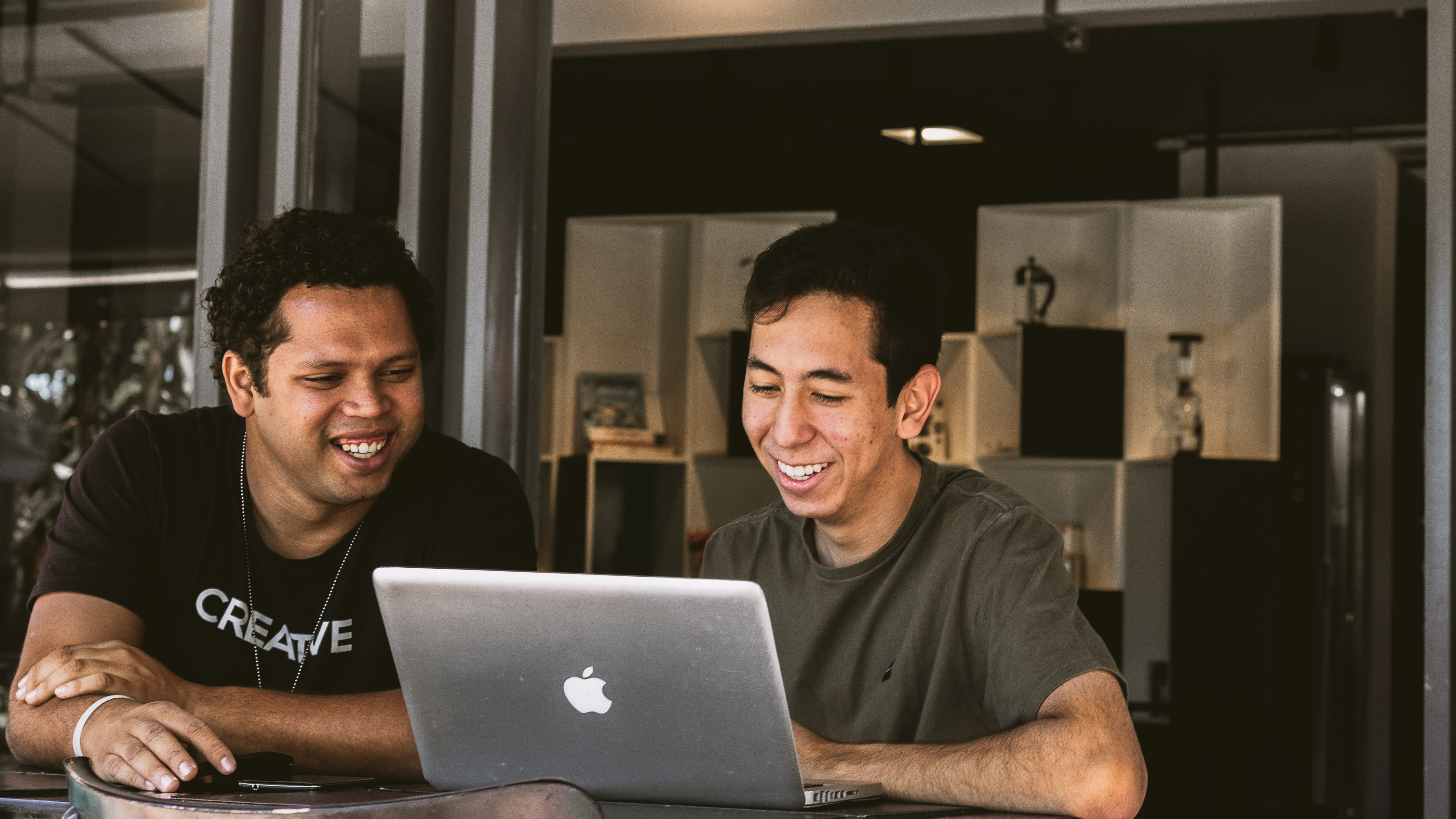 Two young adults smiling and looking at computer together
