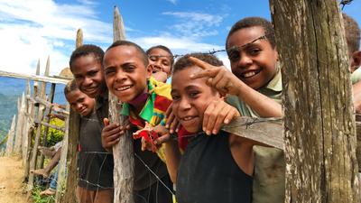 photo of 7 young boys smiling at camera and leaning on wired fence