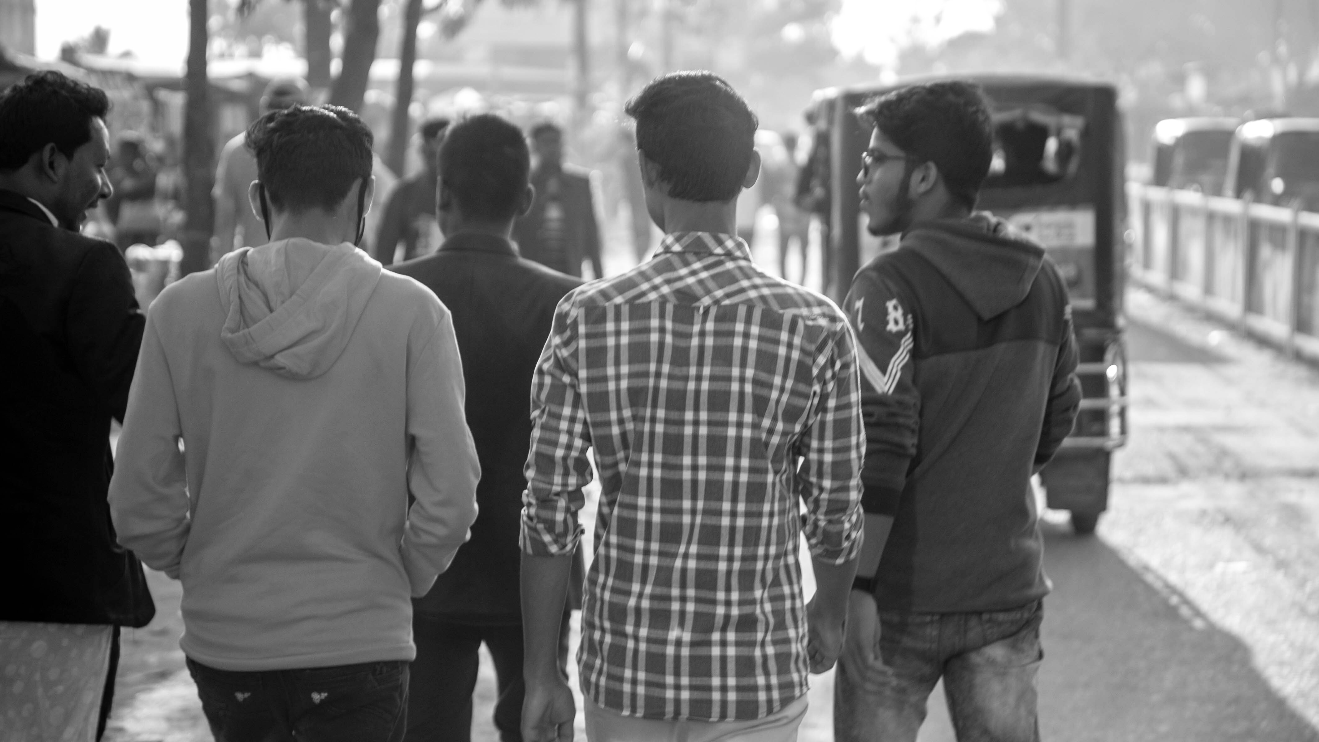Group of young adults walking through street market black and white